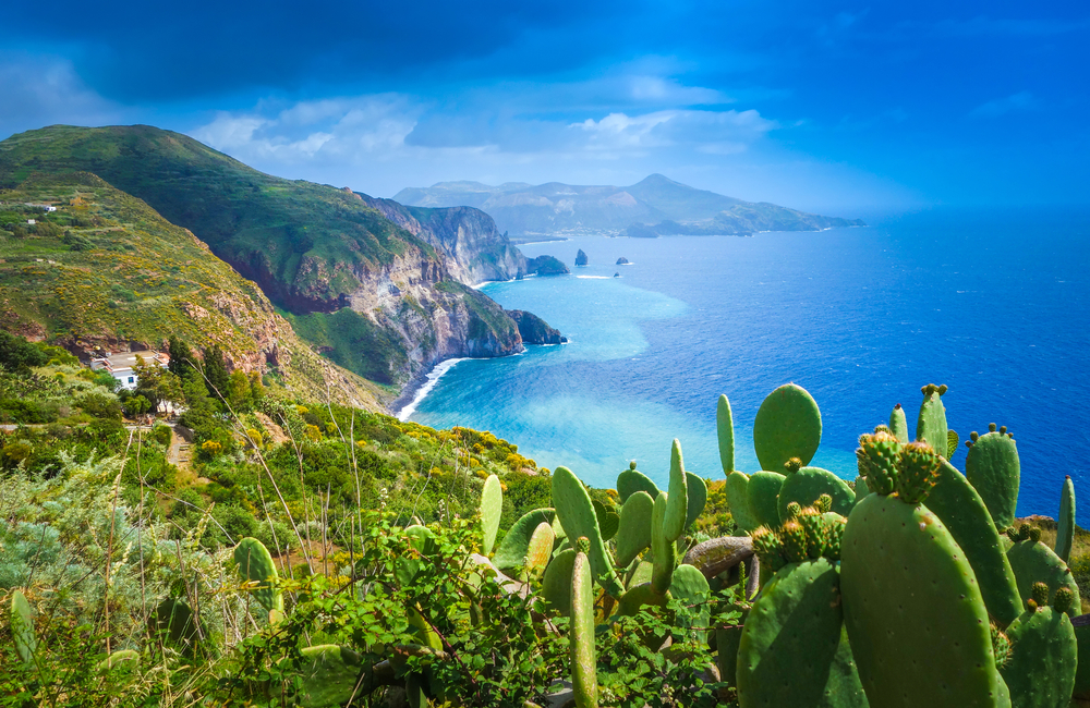 rugged coastline, cacti are on the edge of the mountain overlooking water below, one of the best places to visit in europe in august 
