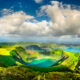 Green mountains with green lake and clouds in between