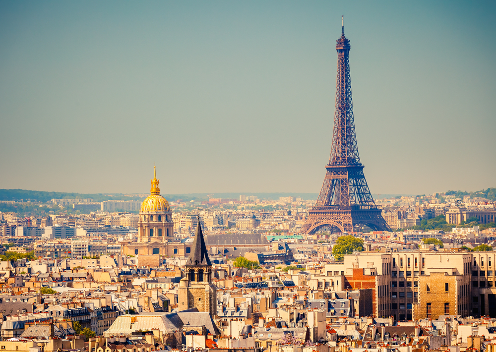 the Eiffel Tower is towering over other buildings in Paris, France on a cloudless day, one of the best places to visit in Europe in august 