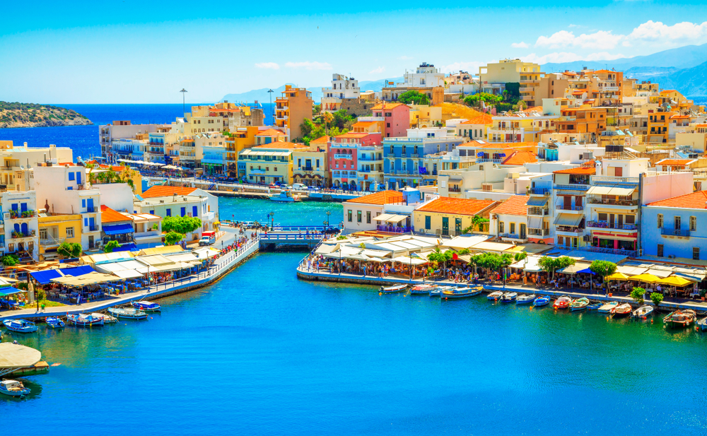 buildings of different color are on an island and mainland, bright summer day, boats docked in the water