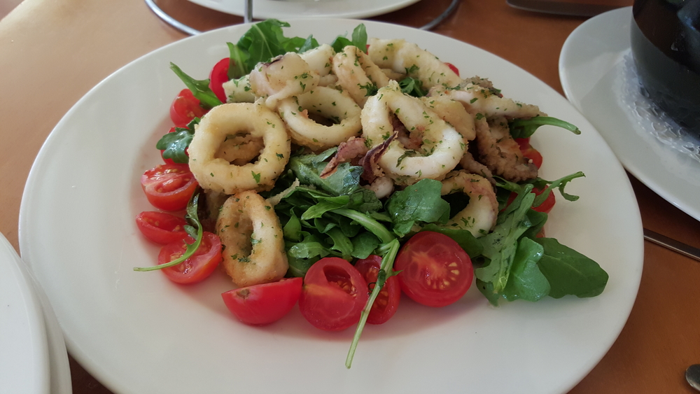 a plate of grilled octopus, arugula and fresh tomatoes