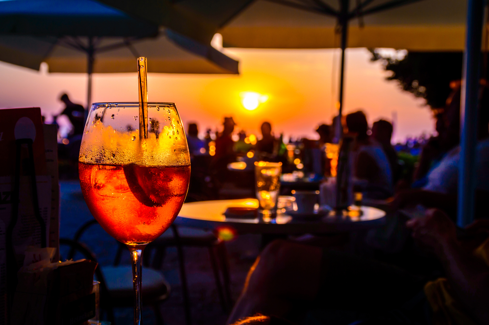 a aperol spritz drinks overlooking the sun setting in a bar