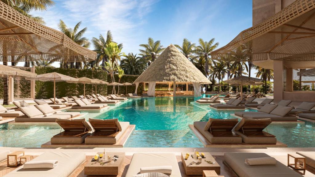 Beautiful pool at Almare Isla Mujeres surrounded by loungers, palm trees, and a cabana bar. 