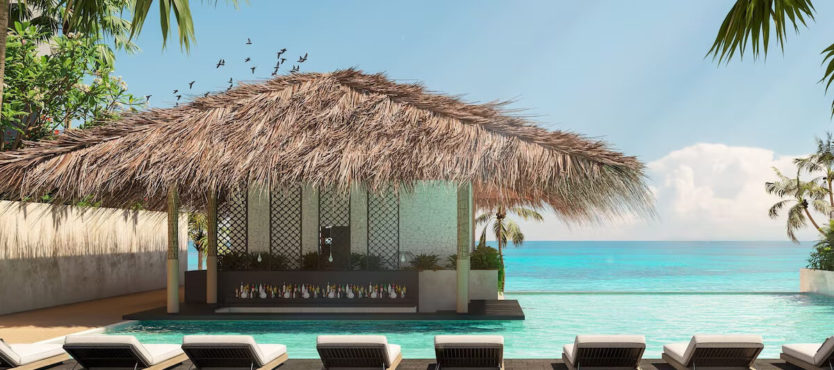 A pool with the ocean in the foreground and a swim up bar in the pool at the Marriott Cancun, one of the best Marriott all inclusive resorts.