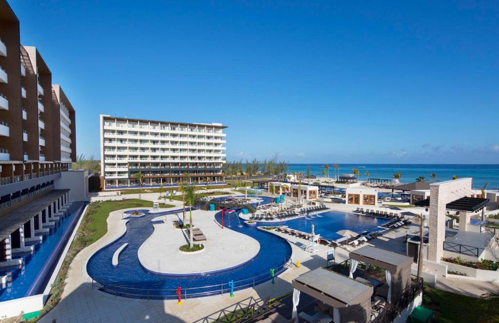 View of the lazy river and one of the pools from a balcony with the ocean in the distance. 