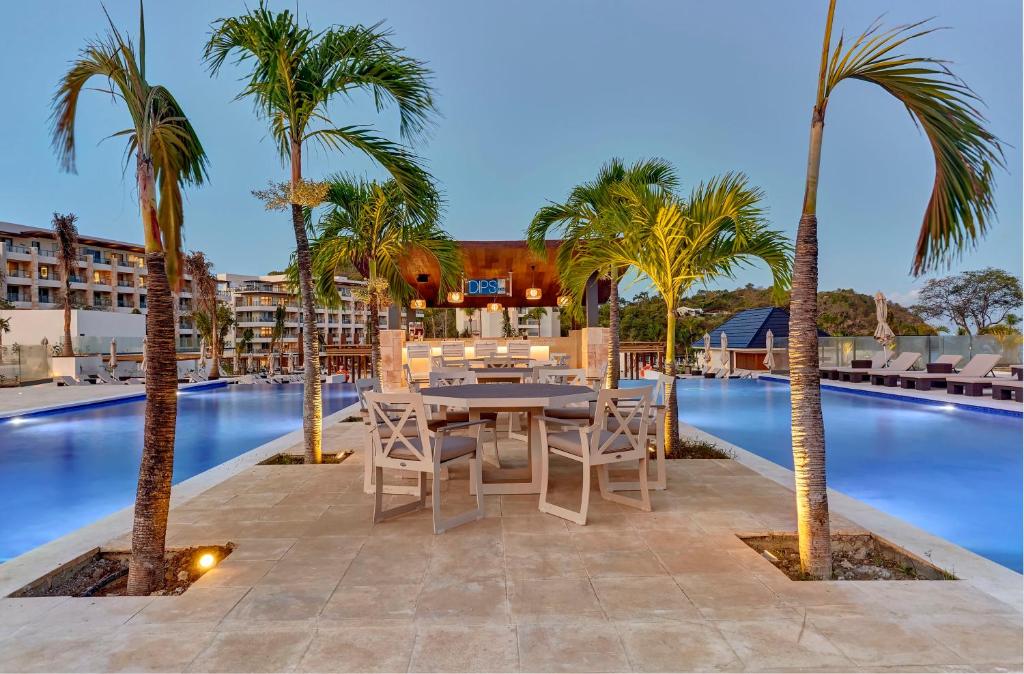 A walkway with palm trees on the outside and pools outside of that. 