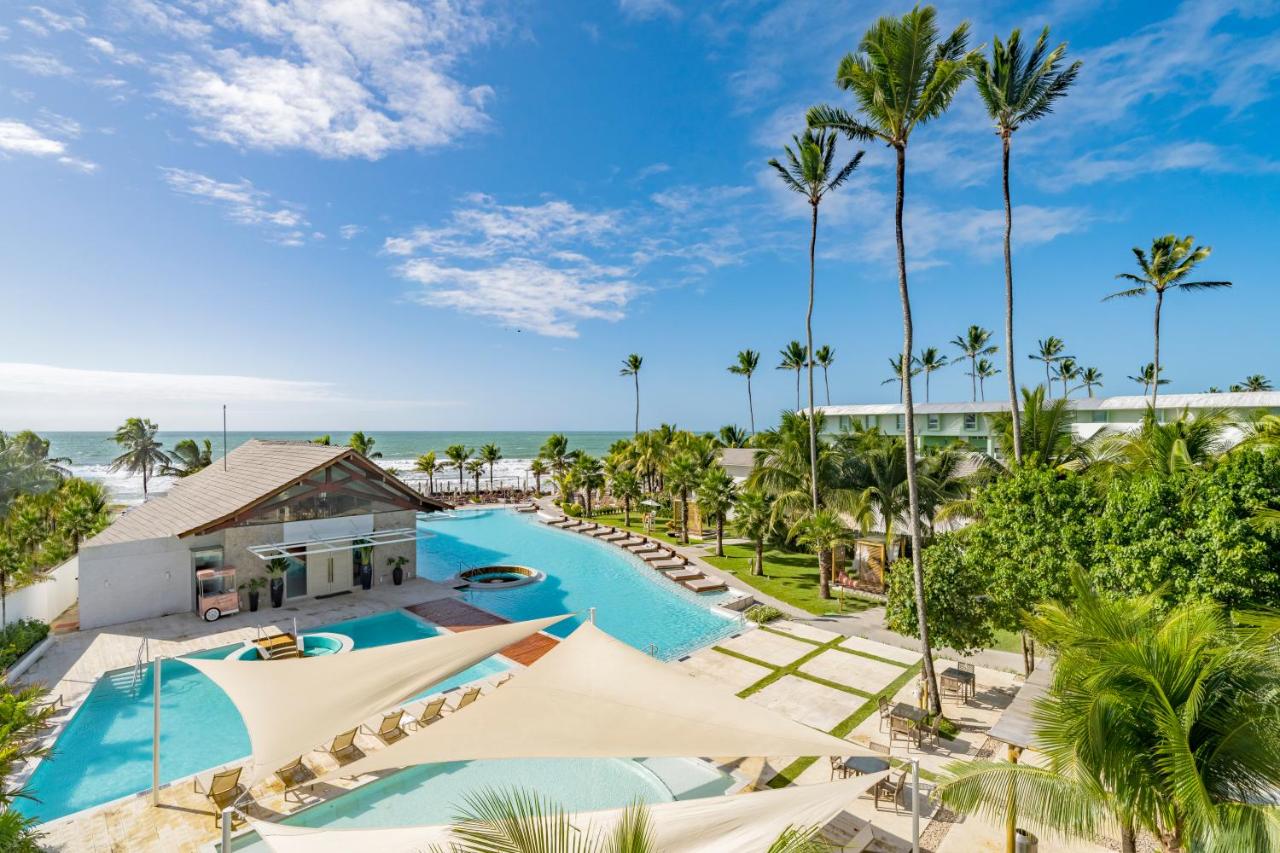 View overlooking the pool with canopies, palm trees, and the ocean in the background. 