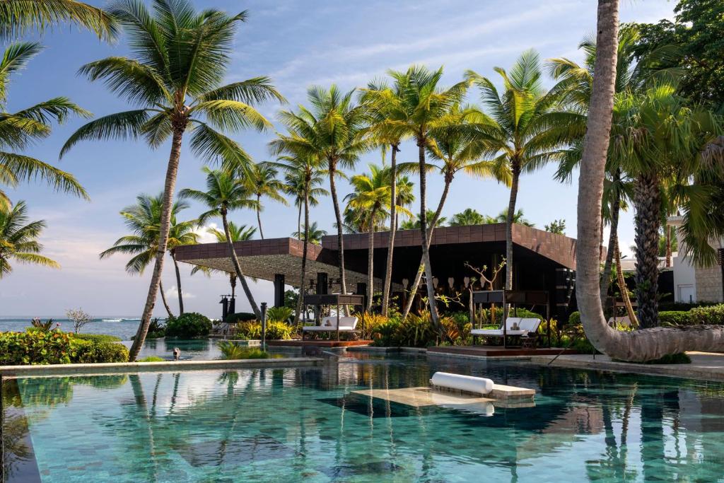 Hotel pool overlooking the ocean. There is a bar in the background and a seating area in the middle of the pool. 