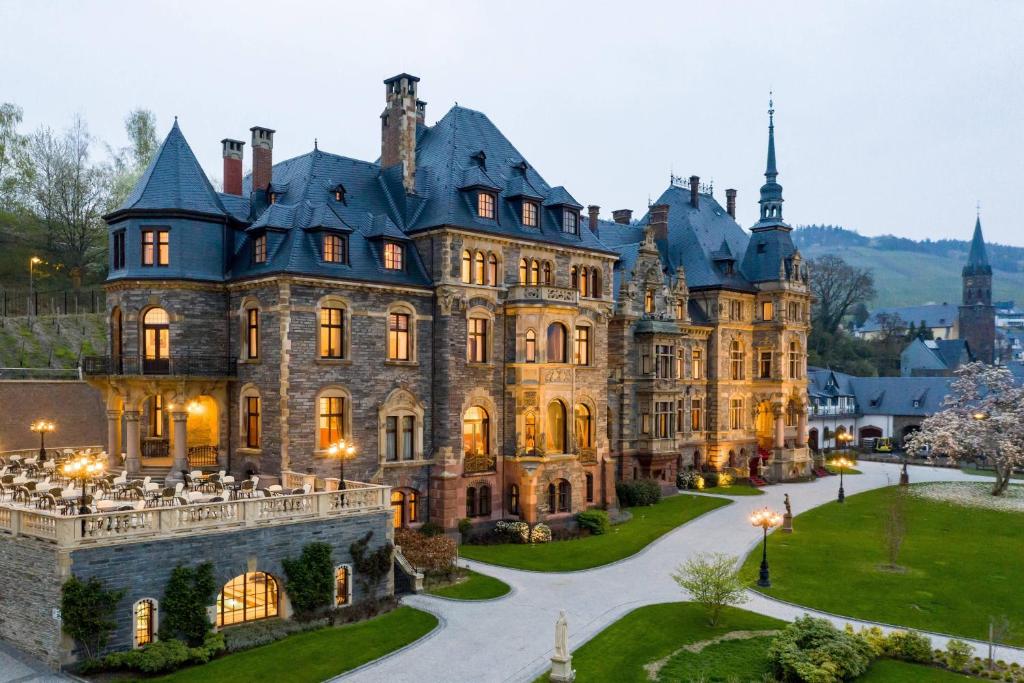 A fairytale looking castle hotel at dusk with the light on and mountains in the background. 