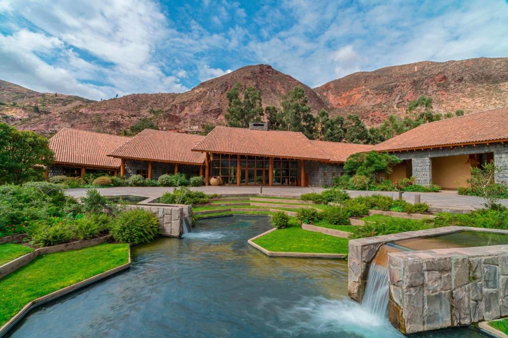 Swimming pool in the foreground with a building in the background and mountains behind the building.  