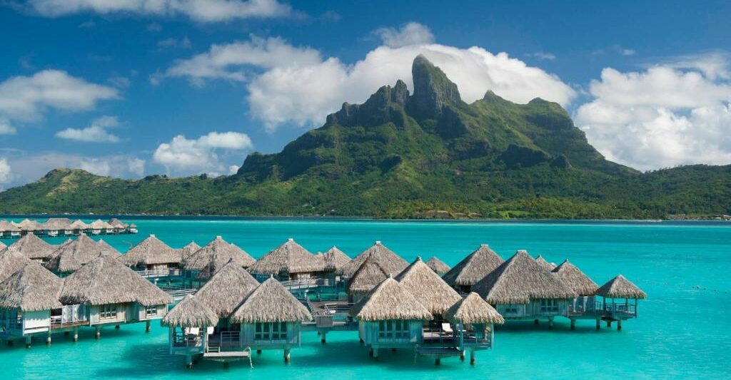 overwater bunglaows in pretty blue water in bora bora with mountains