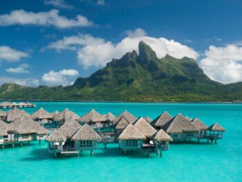 overwater bunglaows in pretty blue water in bora bora with mountains