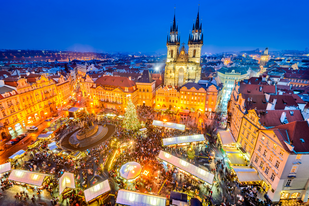aeiral photo of a christmas market in a town square, there is a christmas tree in the middle and stalls and tents around it, one of the best places to visit in europe in december 