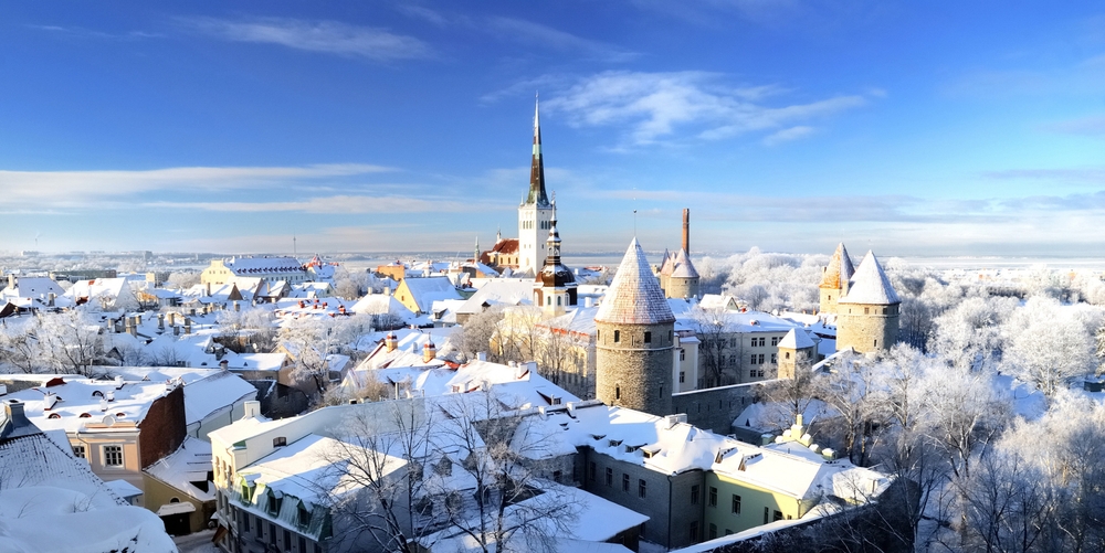 snow covered buildings and trees, mostly clear sky, spires and towers can be seen poking up amongst the buildings 
