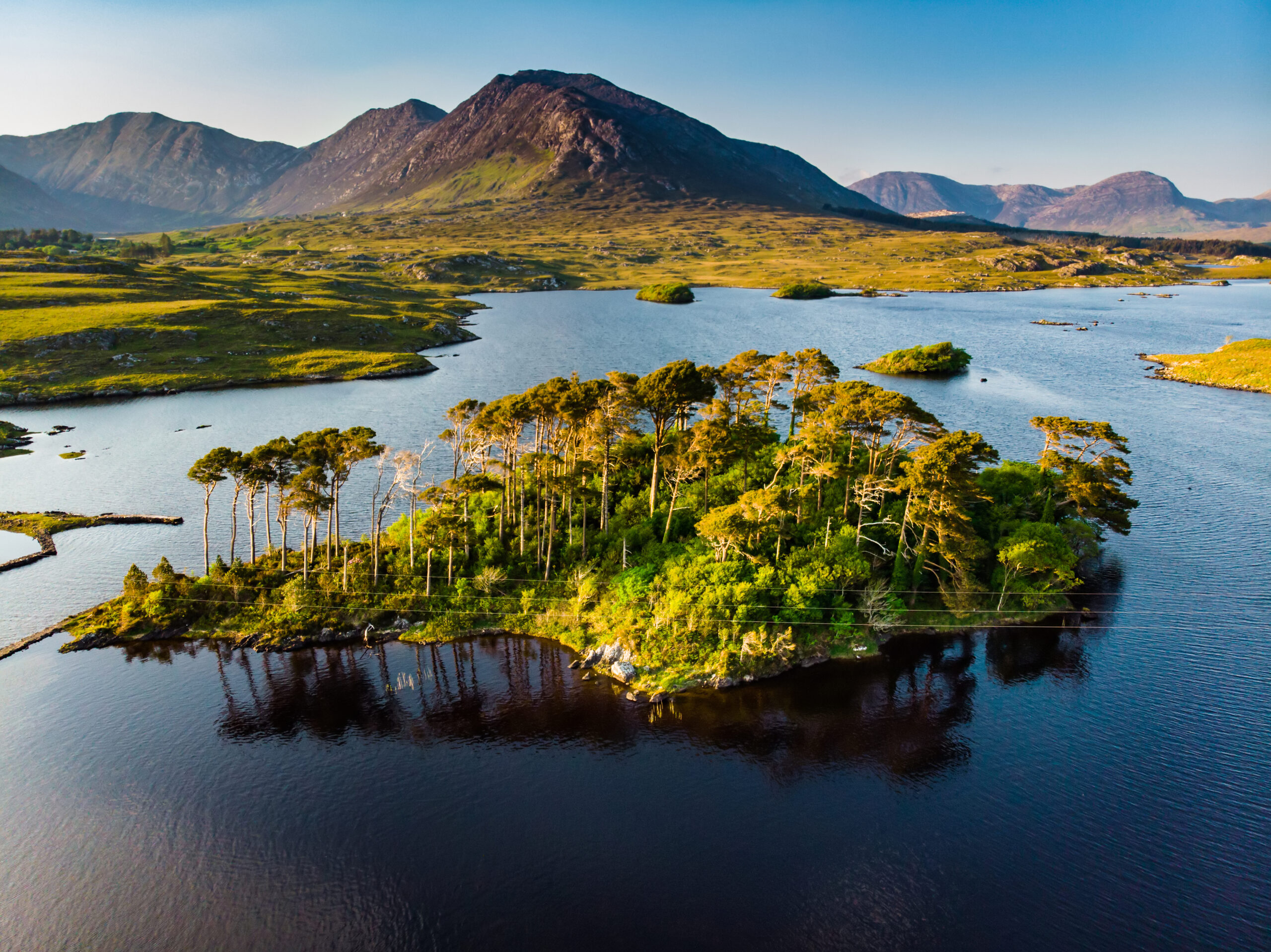 Aerial view of the famous pine island in Derryclare Lough, Ireland with Twelve Bens Mountain Range in the background. 