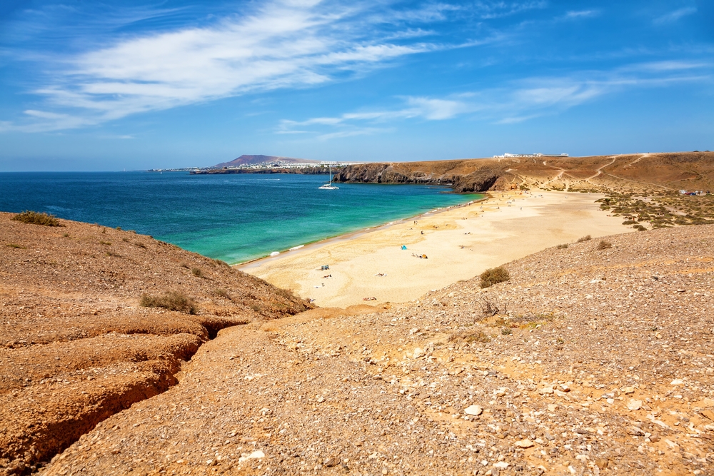 turquoise water and expansive beach surrounded by volcanic rock is the canary islands