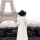 a girl in long coat facing Eiffel Tower