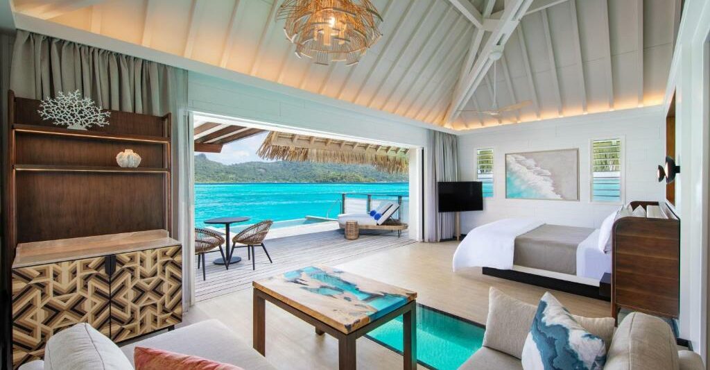 living room and bedroom with a large open dorrwar to a balcony. It is one of the Overwater Bungalows with Glass Floors