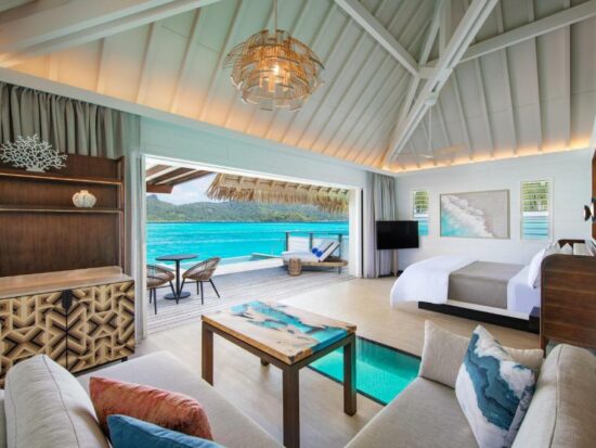 living room and bedroom with a large open dorrwar to a balcony. It is one of the Overwater Bungalows with Glass Floors
