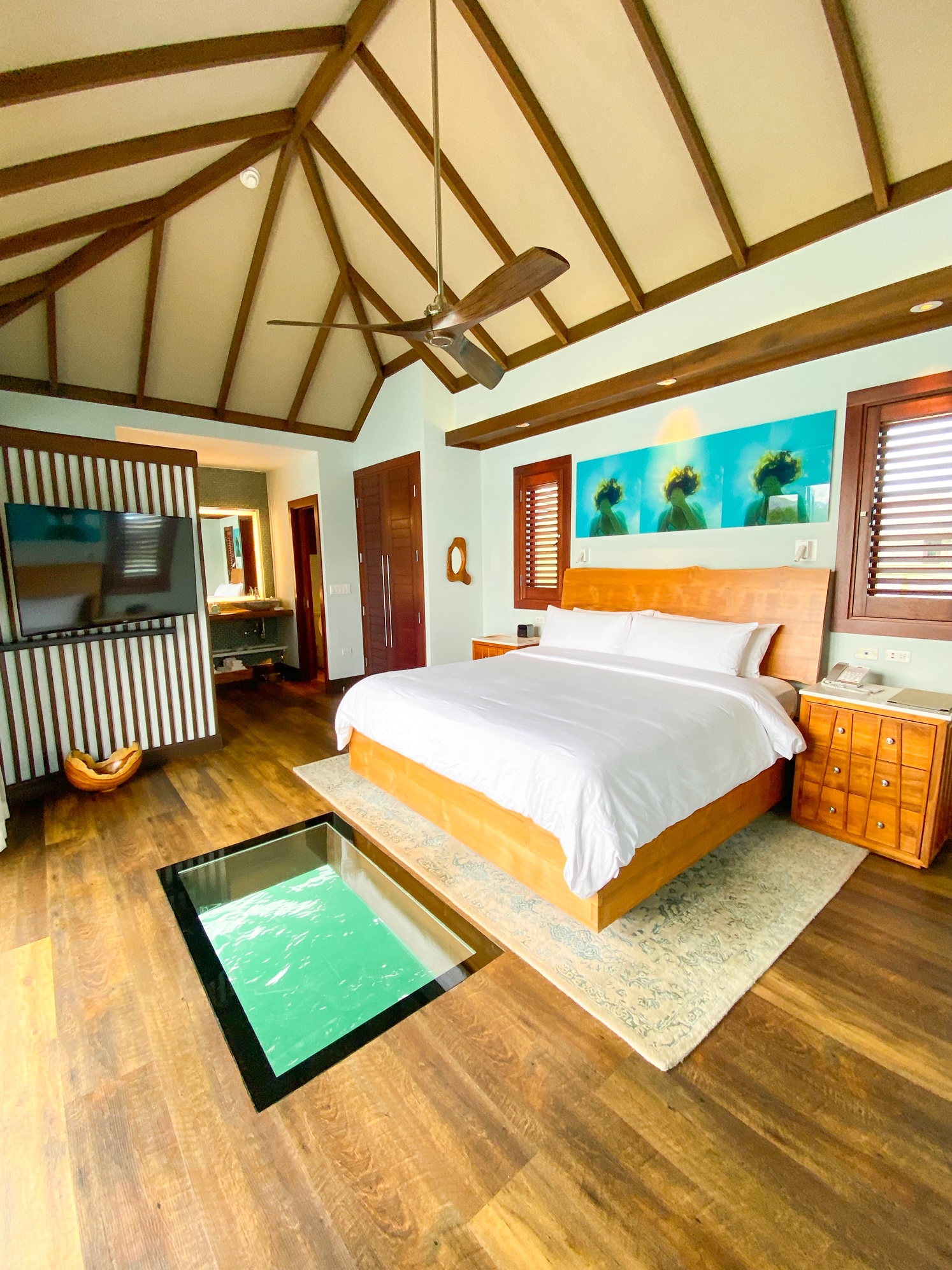 Bedroom showing bed and glass floor to ocean below. One of the Overwater Bungalows with Glass Floors .
