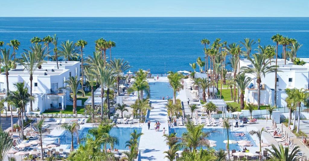 various hotel pools in a complex with palm trees all around and hotel rooms in various places . One of the best all-inclusive resorts in Europe