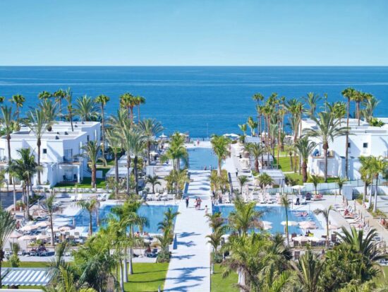 various hotel pools in a complex with palm trees all around and hotel rooms in various places . One of the best all-inclusive resorts in Europe