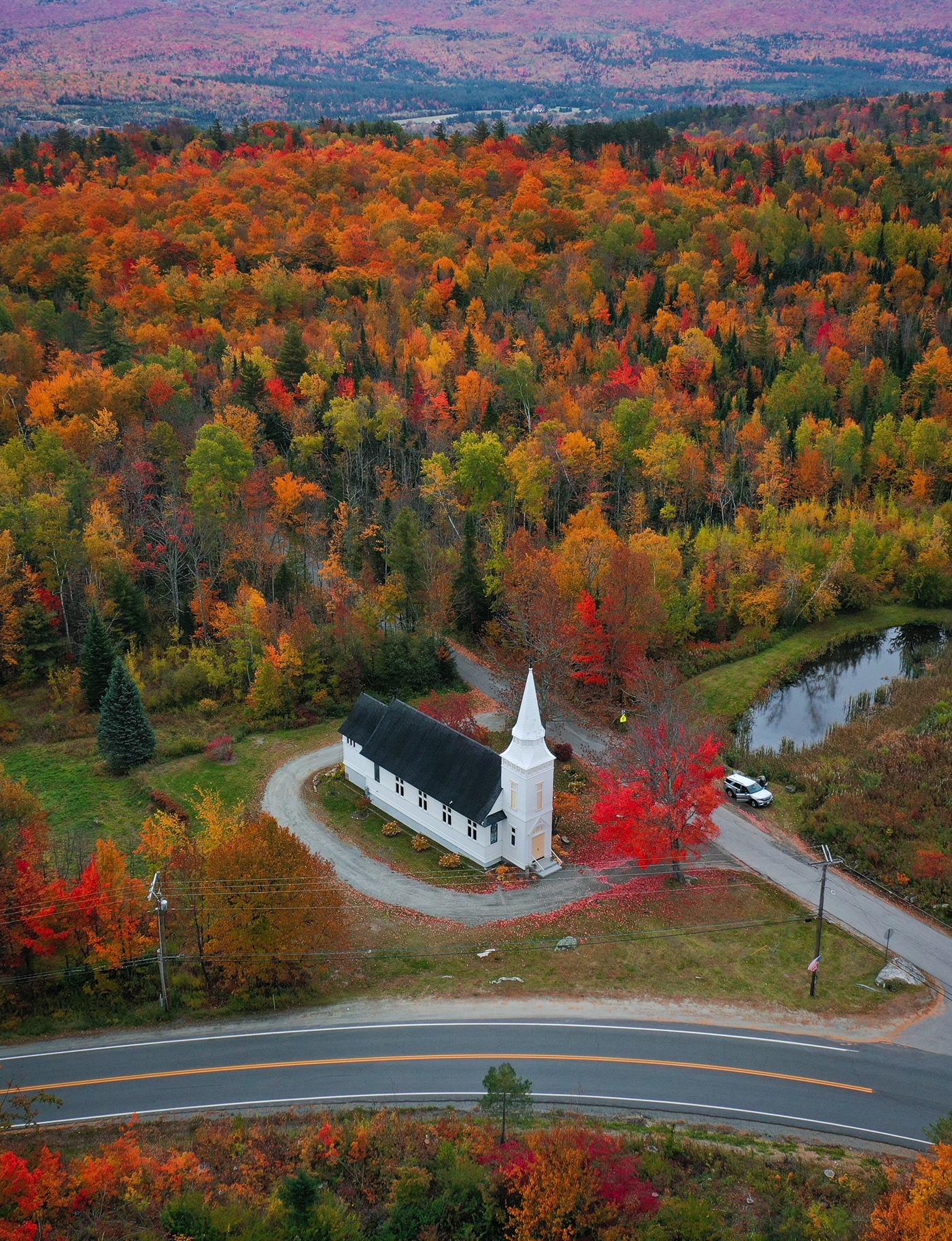 An overhead shot of a white church contrasts the color to the yellow, red, orange and green leaves around it: these views are things you want to see and so make sure you know what mistakes to avoid on a fall foliage trip.