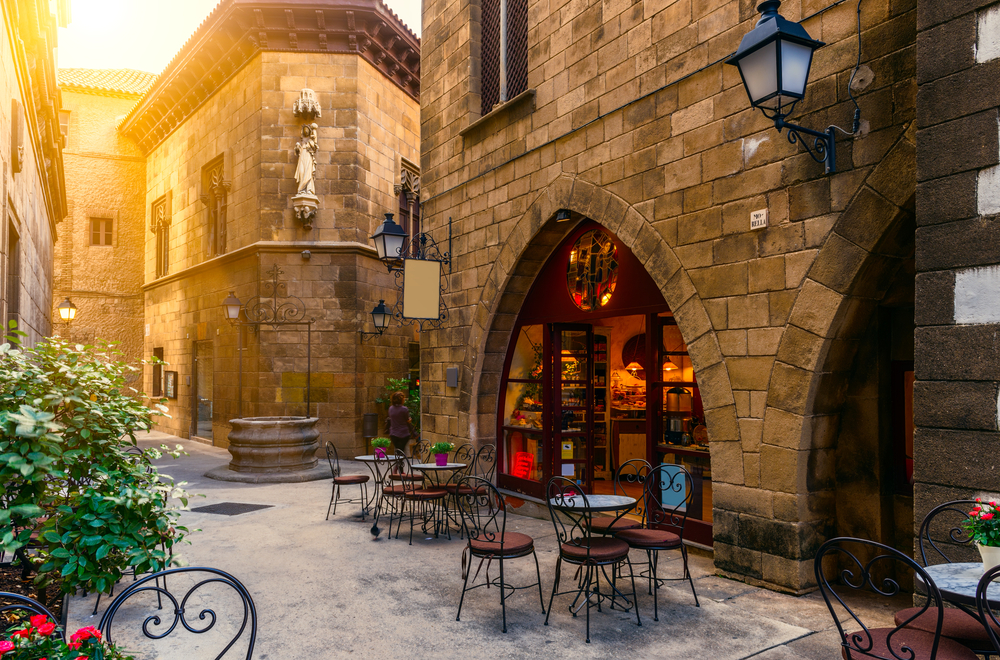 A corner cafe shows empty chairs and tables out front, ready to welcome guests from the warm glow of the lights inside.