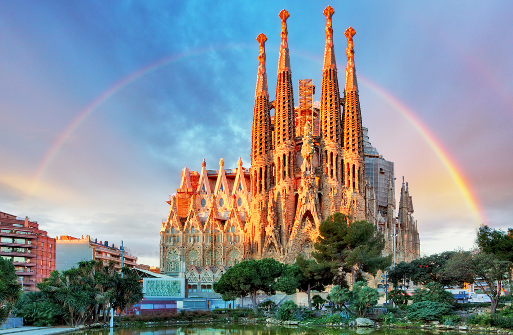 A rainbow arcs over a castle in Spain: seeing these places are an important component of mistakes to avoid in Spain.