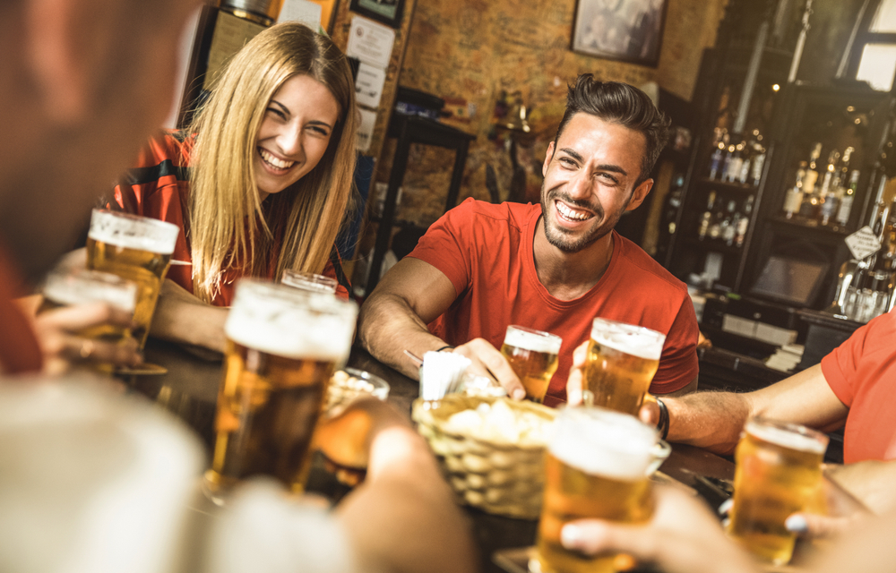 Friends having a pint if beer and laughing the article is about planning a trip to London