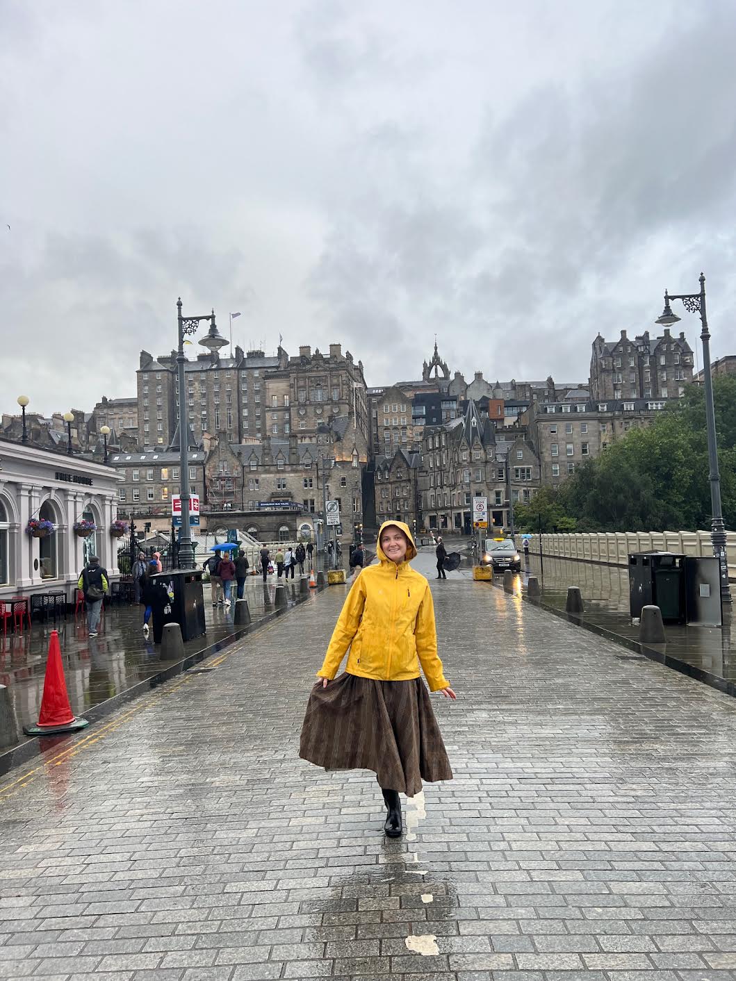 a girl in yellow raincoat and boots staining in front of Waverly Station