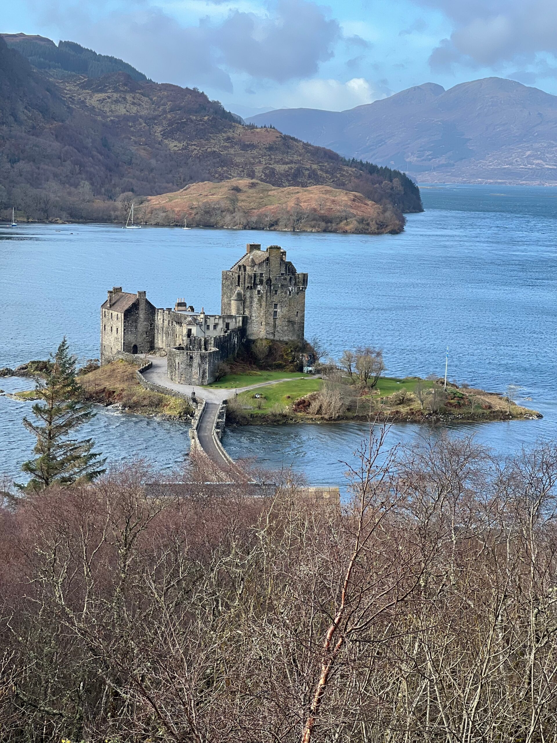 Eilean Donan Castle, is castle out on an island surrounded by water and forest in the backdrop