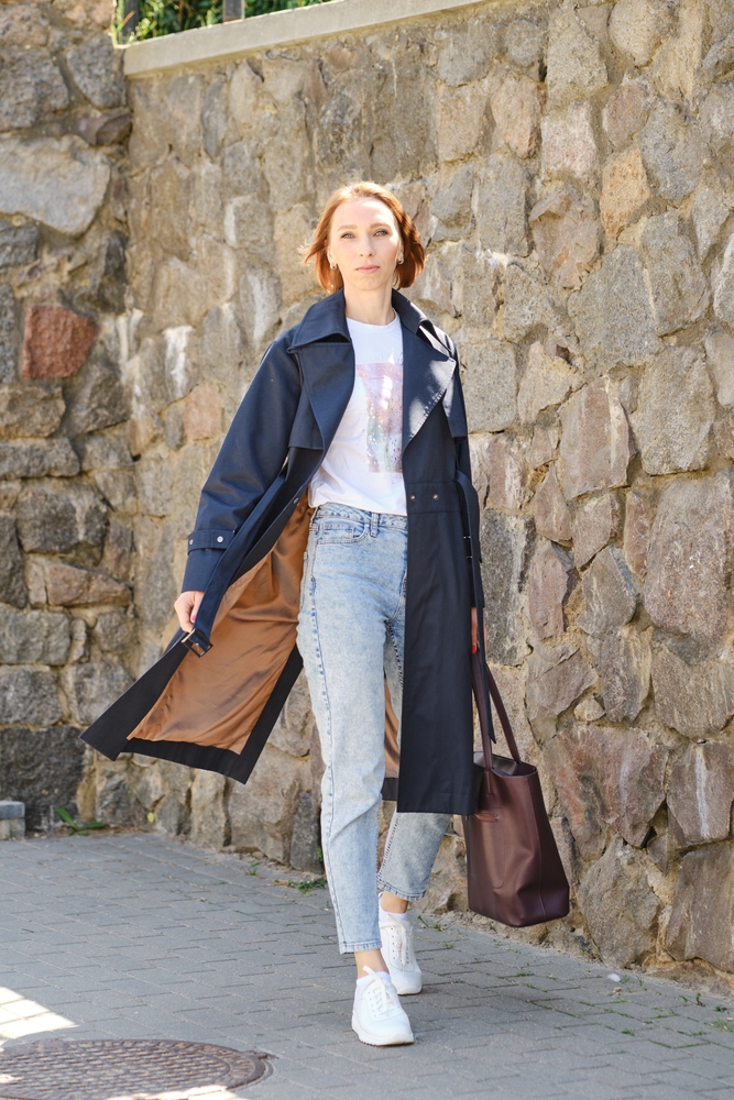 a woman walking the cobblestone street in sneakers and an overcoat