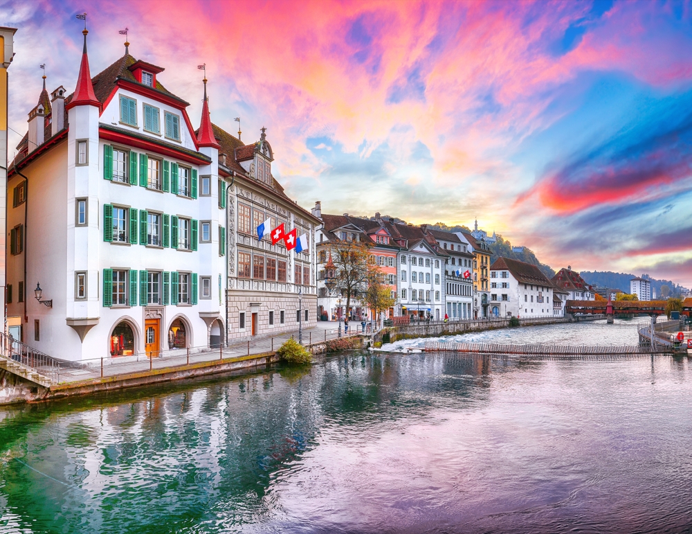 In a northern European country, tall white and historic buildings are pressed flush against each other during a sunset, overlooking the water, and you can see this too if you know what things to buy from Amazon for Europe.