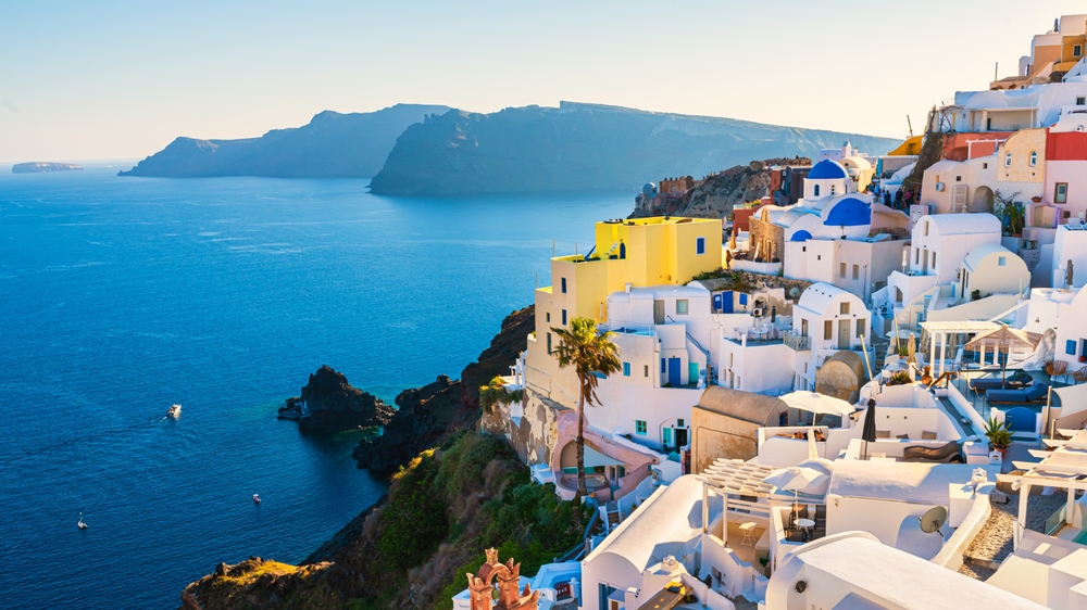 In Greece, the blue dome-topped buildings are stacked on top of one another in the city, leaning over the cliffside and blue waters below.