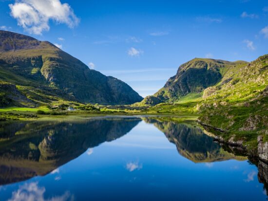 The rolling hills and cliffs of the green land of Ireland come together and reflect over a glassy lake: you can see these stunning views when you prep for your trip and know which things to buy from Amazon for Ireland!