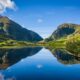 The rolling hills and cliffs of the green land of Ireland come together and reflect over a glassy lake: you can see these stunning views when you prep for your trip and know which things to buy from Amazon for Ireland!