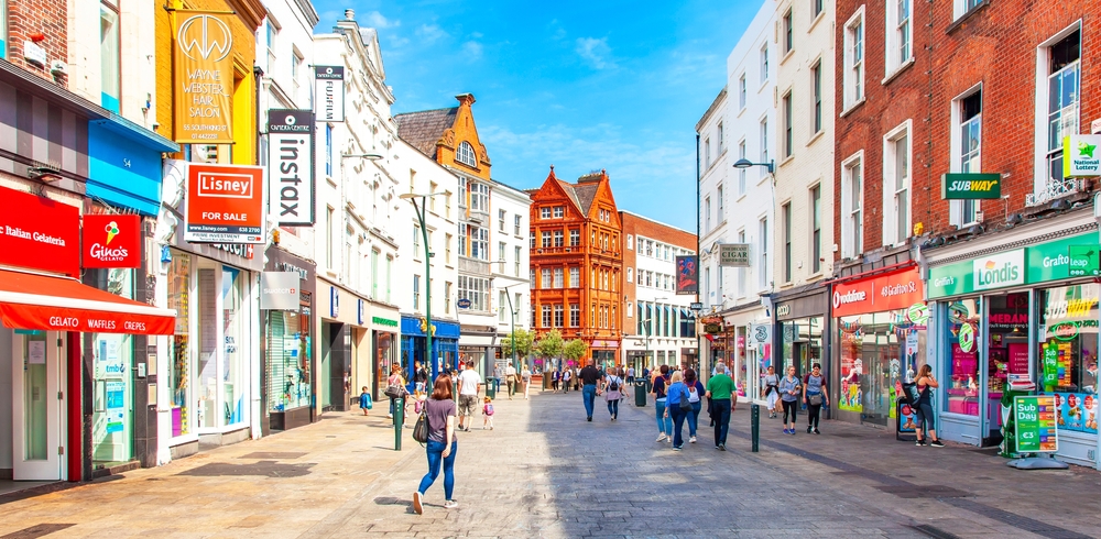 During a brightly light day, the streets of Dublin glow with storefronts and shops and people walking.