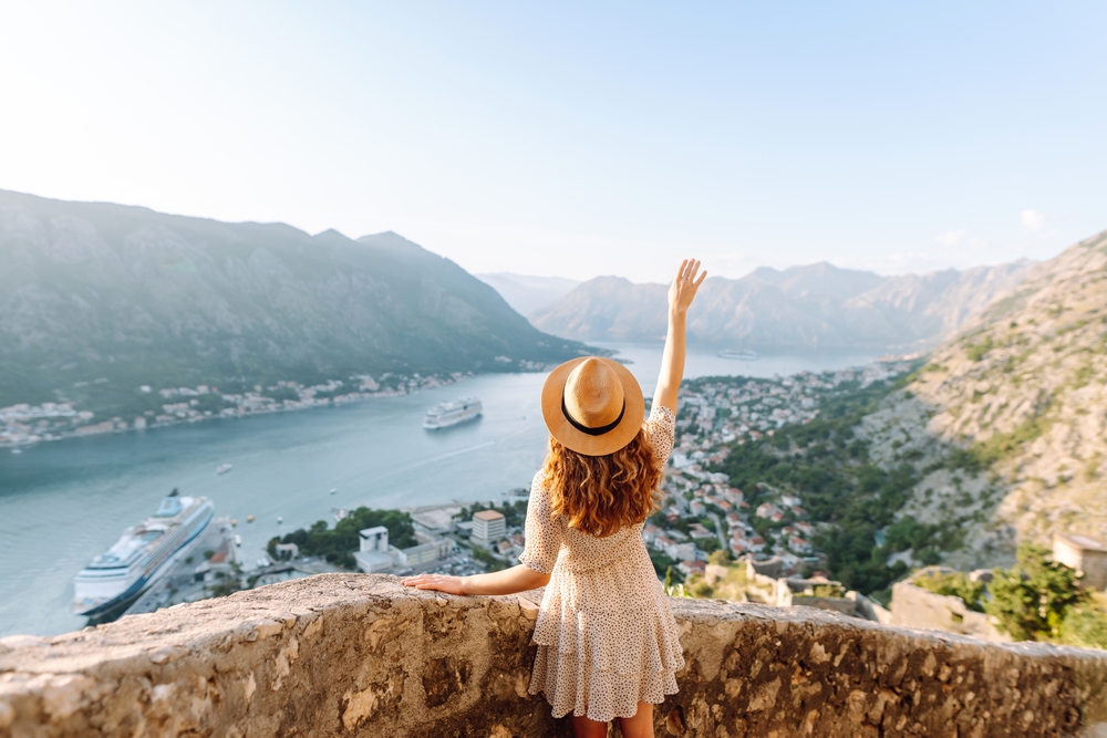 A woman raises her arm in excitement as she leans over the cobblestone walls in Northern italy 