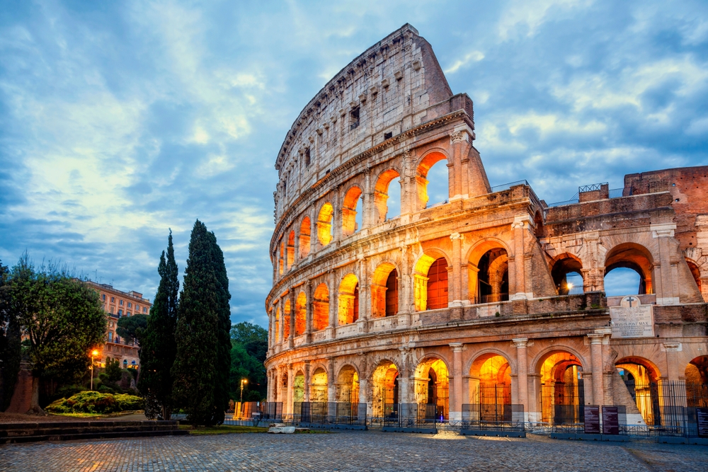 A photo of the colosseum at night glows with golden lights, and this is something you can see when you pack accordingly and know what things to buy from Amazon for Italy.