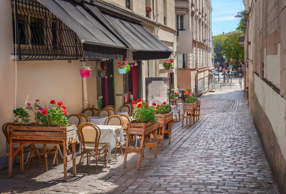 A little cafe with cute red flowers, tiny tables, and wooden chairs sits hidden on a cobblestone side street: these hidden gems can be found when you know what things to buy from Amazon for Paris.
