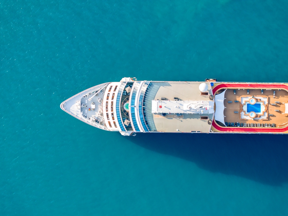 An overhead shot shows the front half of a cruise ship and its main deck with chairs and pools, all of which you can enjoy when you know what things to buy from Amazon for a cruise.