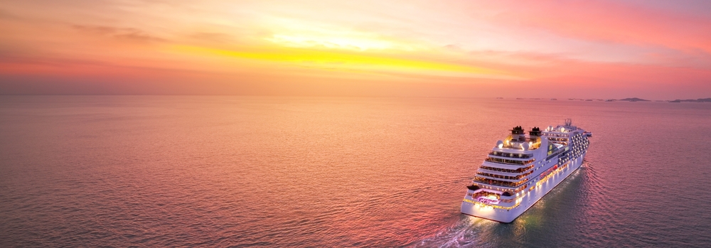 A cruise cuts through the water during a pink sunset, visitors content becuase they knew what things to buy from Amazon for a cruise