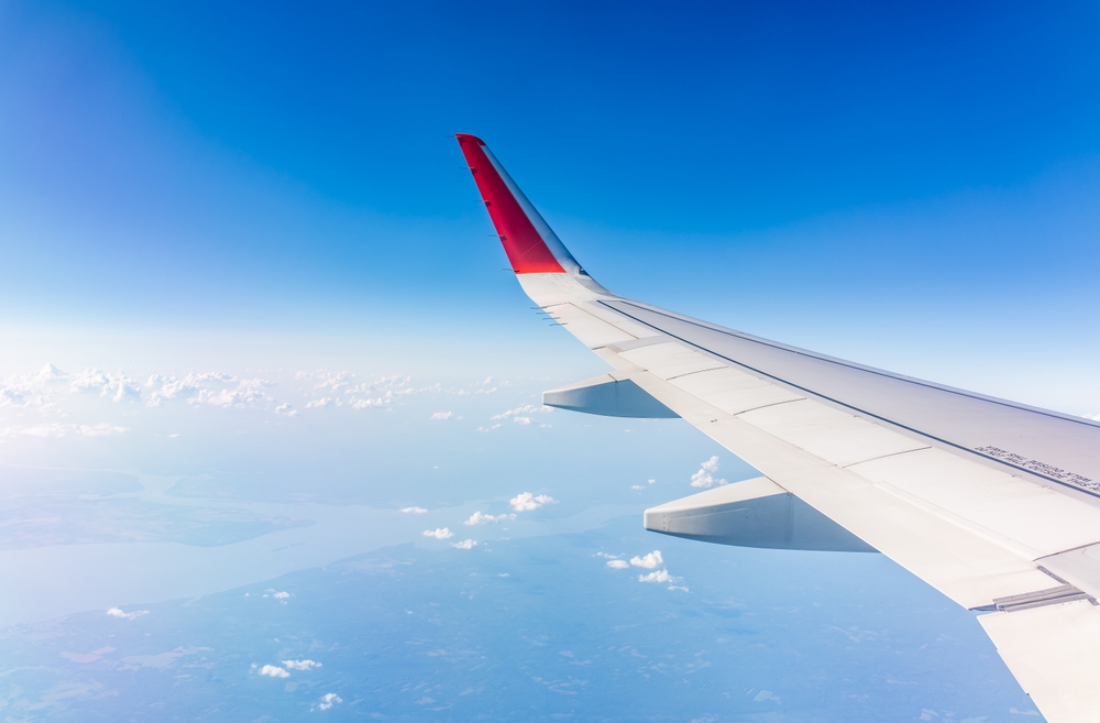 When knowing what things to buy from Amazon before flying, you want to consider comfort, and class, as seen in this photo: the view of the plane's wing soars above tiny towns below and clouds.