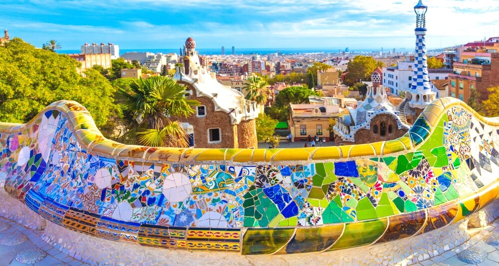 Barcelona city panoramic view of Parc Guell with colorful tiles overlook the city beneath it. The article is about things to buy from Amazon before going to Spain.