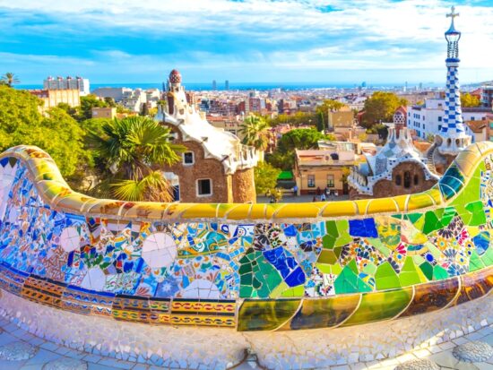 Barcelona city panoramic view of Parc Guell with colorful tiles overlook the city beneath it. The article is about things to buy from Amazon before going to Spain.