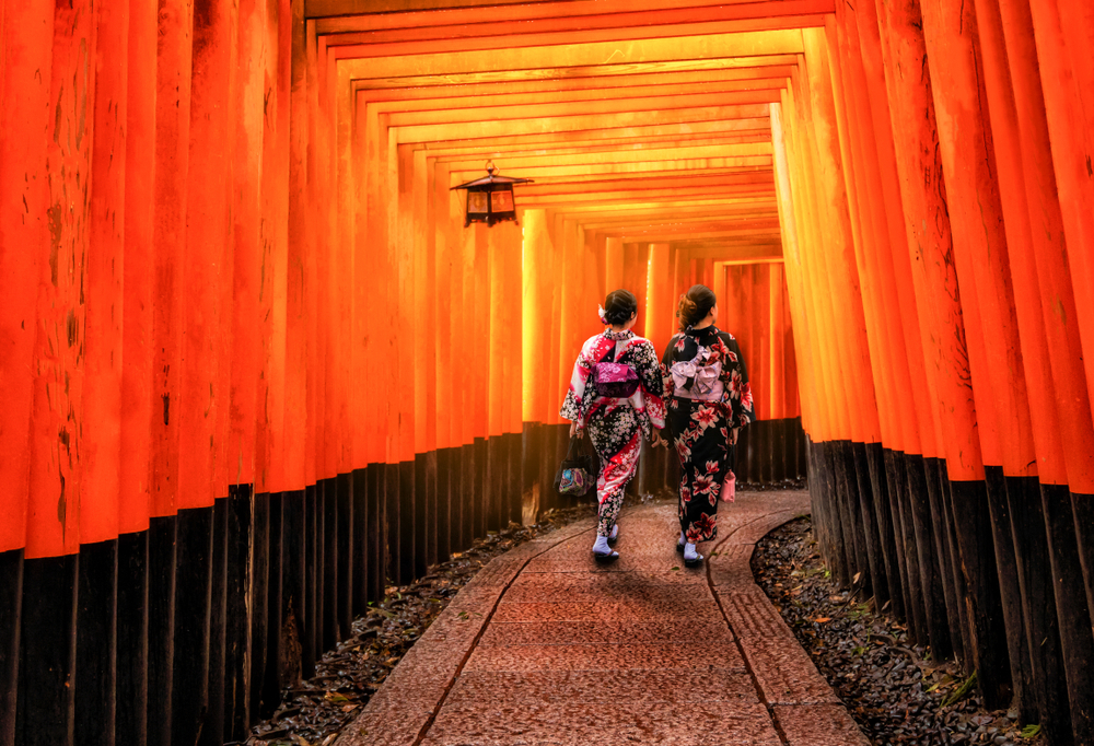 Asian traveler wearing traditional Japanese kimono walking in Fushimi Inari Shrine in the old town of Kyoto, Japan. Article is about things to buy from Amazon for Japan.