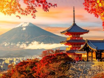 Kiyomizu-dera temple in Kyoto and mount Fuji at autumn sunset, Japan. it is sunset during the fall with fall foliage leaves framing the building with the mountain in the background. Article is about things to buy from Amazon for Japan.