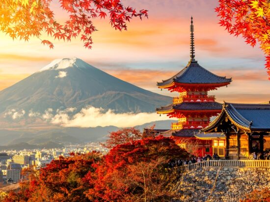Kiyomizu-dera temple in Kyoto and mount Fuji at autumn sunset, Japan. it is sunset during the fall with fall foliage leaves framing the building with the mountain in the background. Article is about things to buy from Amazon for Japan.