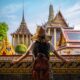 A woman overlooks the structure of colorful buildings in Asia, as she leans on an open window with ornate and colorful designs, full well knowing what things to buy from amazon for vacation and how they helped her for this trip.